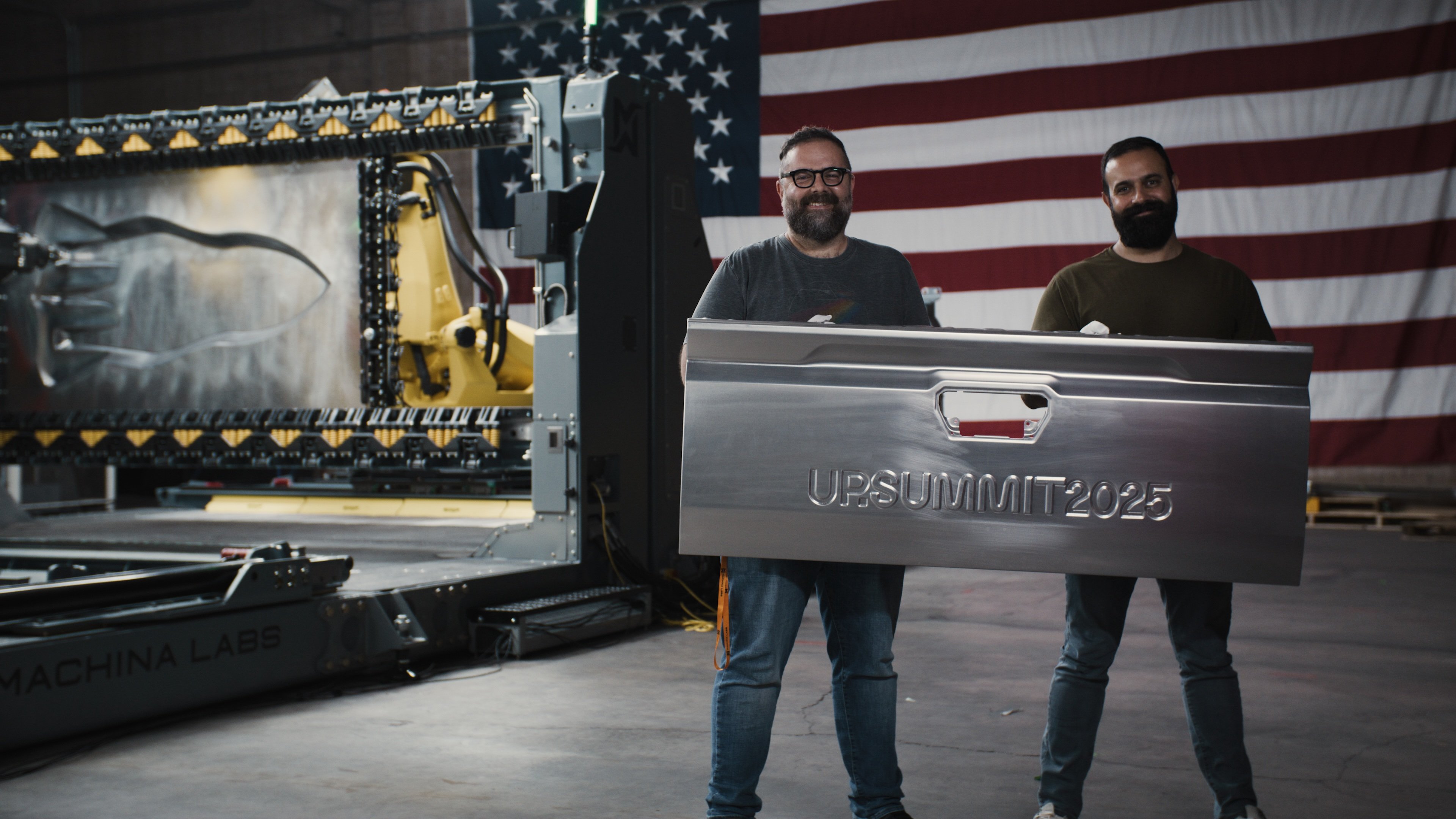 Machina-Labs co-founders hold a Toyota Tacoma tailgate that was customized with the RoboCraftsman manufacturing platform.